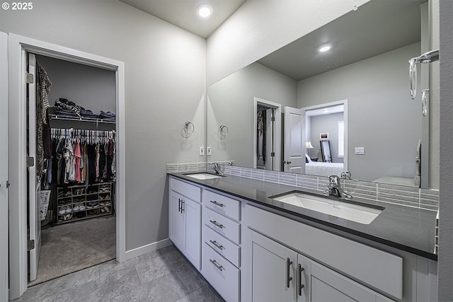 full bath featuring a walk in closet, double vanity, a sink, and ensuite bathroom