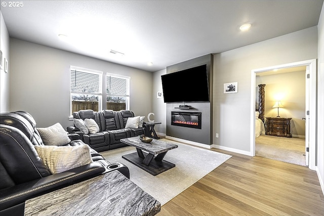 living area with light wood finished floors, baseboards, visible vents, and a large fireplace