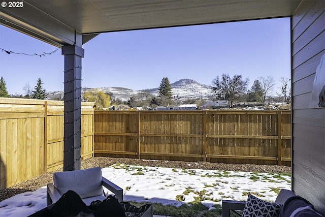 yard covered in snow with a fenced backyard and a mountain view