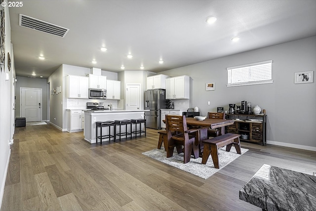 dining space featuring visible vents, baseboards, and wood finished floors