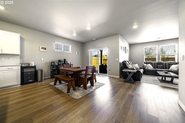 dining area with dark wood finished floors, visible vents, and baseboards