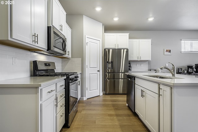 kitchen featuring stainless steel appliances, light wood-type flooring, a sink, and light countertops