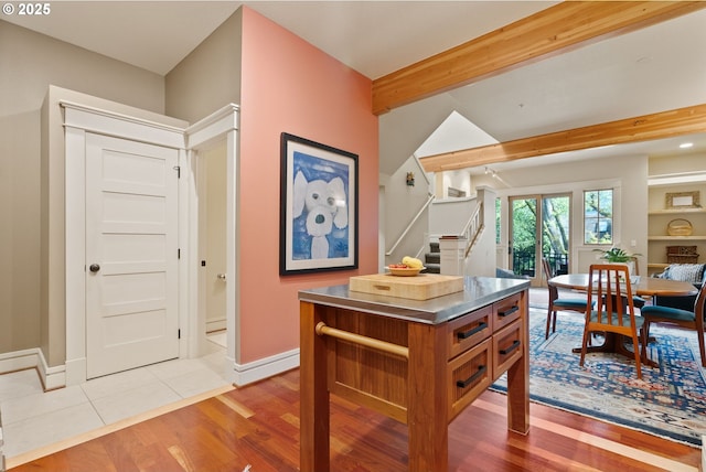 dining space featuring stairs, beam ceiling, baseboards, and wood finished floors