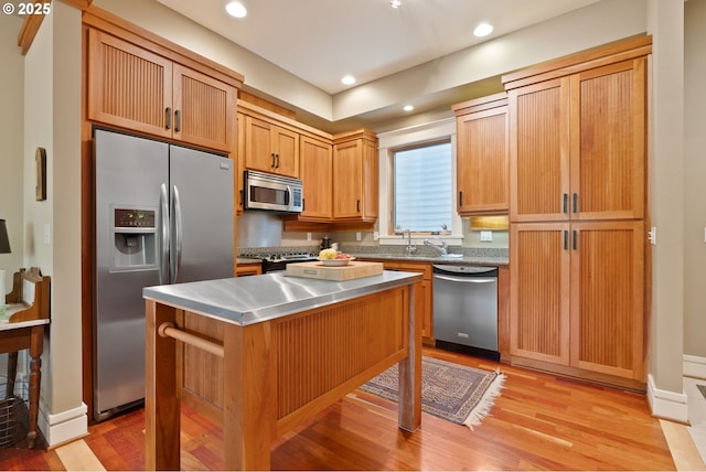 kitchen with stainless steel counters, a center island, recessed lighting, light wood finished floors, and appliances with stainless steel finishes