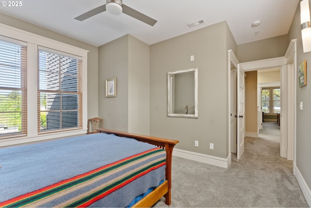 bedroom with baseboards, light carpet, visible vents, and a ceiling fan