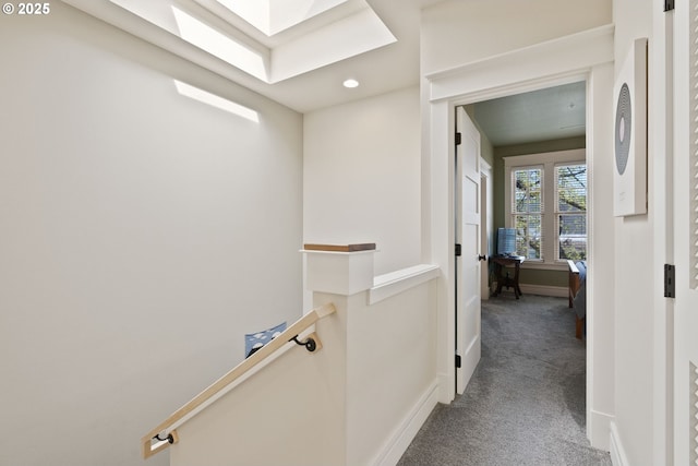 hallway with a skylight, an upstairs landing, recessed lighting, carpet floors, and baseboards