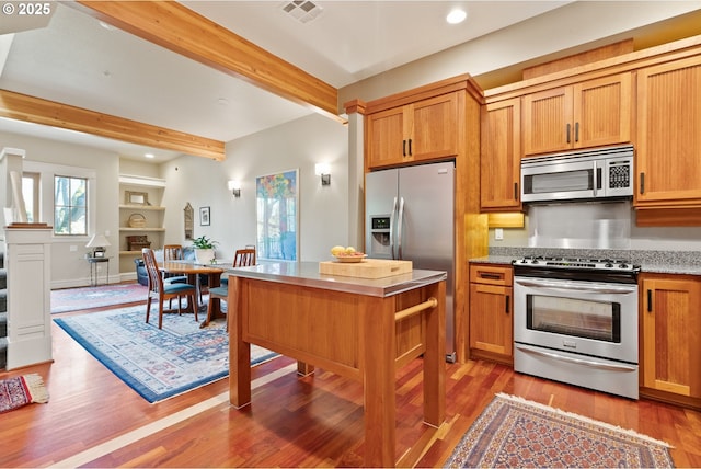 kitchen with stainless steel appliances, visible vents, beamed ceiling, light wood-style floors, and recessed lighting