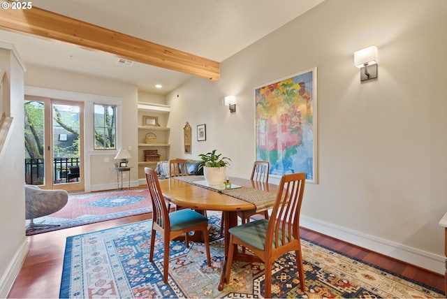 dining room with visible vents, built in shelves, beam ceiling, wood finished floors, and baseboards