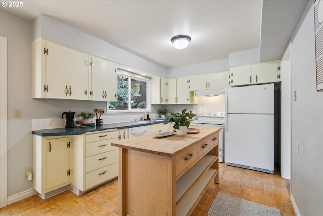 7323 SW Nevada Ter, Portland, OR 97219 - kitchen with white appliances, under cabinet range hood, butcher block counters, a center island, and cream cabinetry