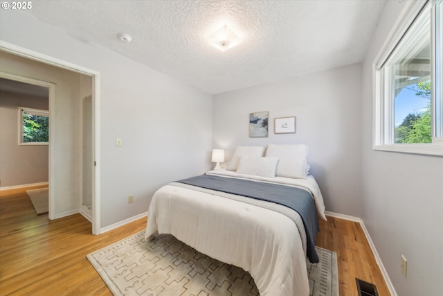 7323 SW Nevada Ter, Portland, OR 97219 - bedroom featuring light wood-style flooring, a textured ceiling, and multiple windows