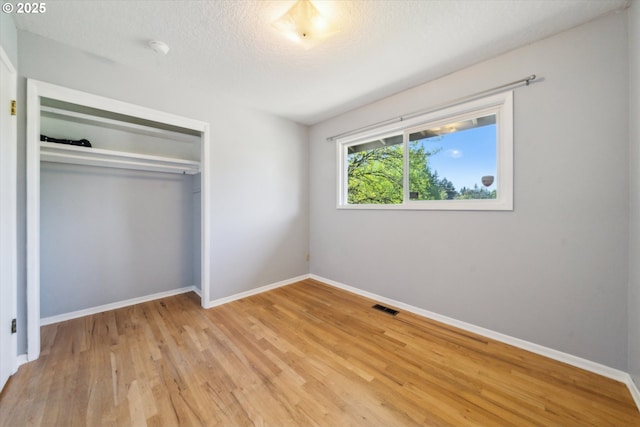 7323 SW Nevada Ter, Portland, OR 97219 - unfurnished bedroom with light wood finished floors, a closet, and a textured ceiling