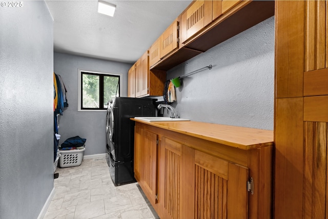 kitchen featuring separate washer and dryer, baseboards, a sink, light marble finish flooring, and wood counters