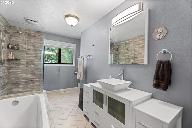 bathroom with a tile shower, a tub to relax in, and vanity