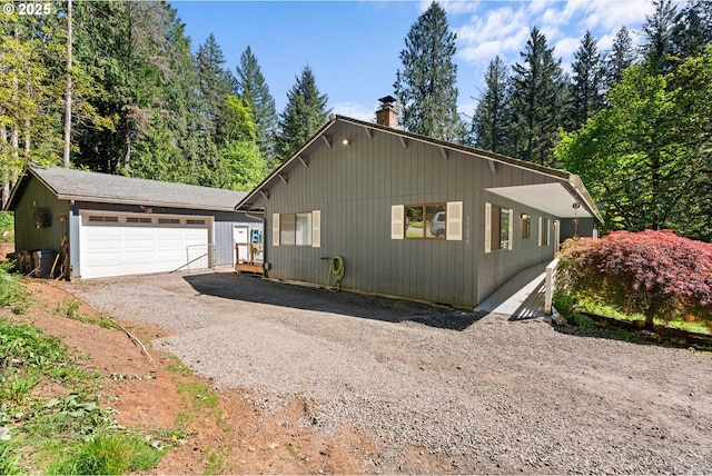 view of home's exterior with a chimney, a garage, and an outdoor structure