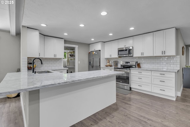 1388 Hillendale Dr, Salem, OR 97302 - kitchen featuring appliances with stainless steel finishes, tasteful backsplash, light stone counters, recessed lighting, and a peninsula