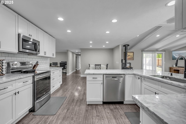 1388 Hillendale Dr, Salem, OR 97302 - kitchen with appliances with stainless steel finishes, a wood stove, recessed lighting, light wood finished floors, and white cabinetry