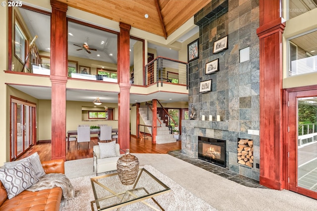 45585 NW David Hill Rd, Forest Grove, OR 97116 - living area with decorative columns, a high ceiling, a tile fireplace, a ceiling fan, and stairs