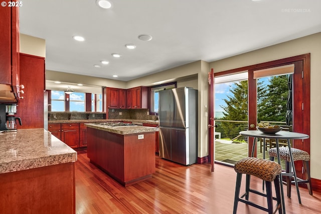 45585 NW David Hill Rd, Forest Grove, OR 97116 - kitchen with freestanding refrigerator, dark wood-style flooring, decorative backsplash, a center island, and plenty of natural light