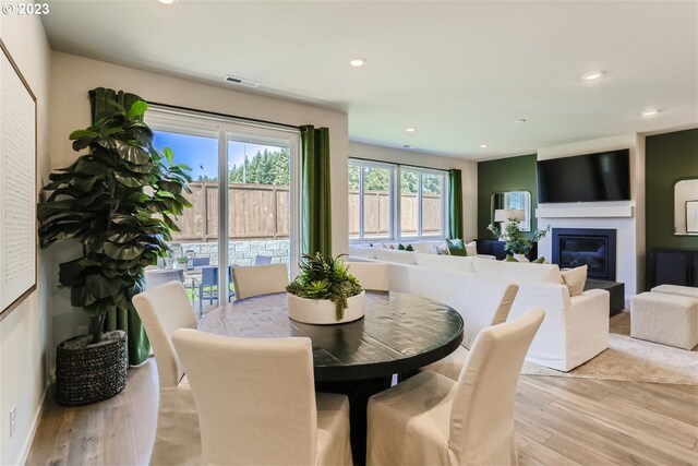 dining room with a glass covered fireplace, visible vents, recessed lighting, and light wood-style flooring