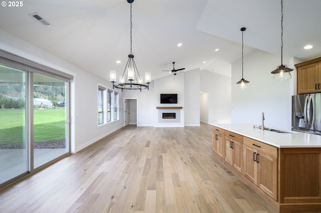 kitchen featuring stainless steel fridge with ice dispenser, sink, vaulted ceiling, and decorative light fixtures