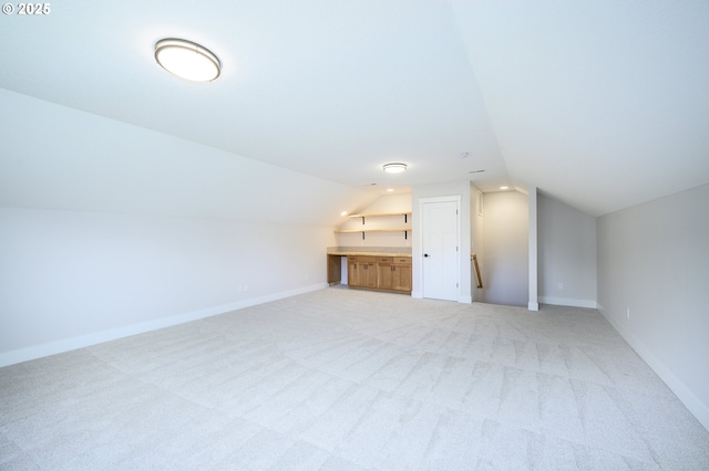 bonus room with lofted ceiling and light colored carpet