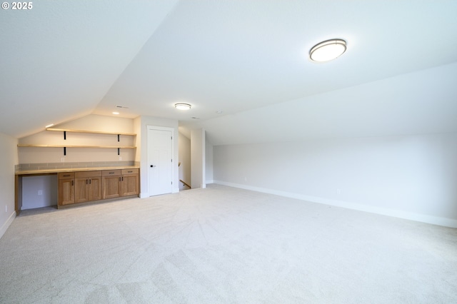 additional living space featuring light carpet and vaulted ceiling