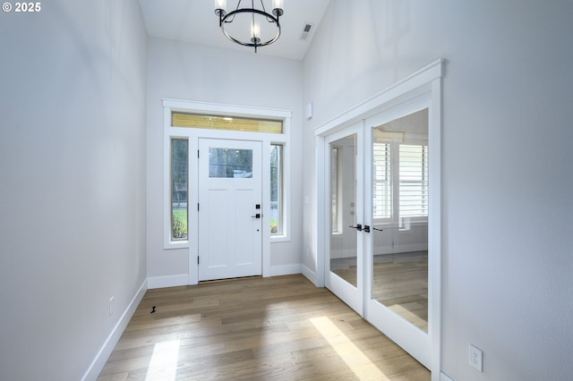 doorway featuring hardwood / wood-style flooring, french doors, and a notable chandelier