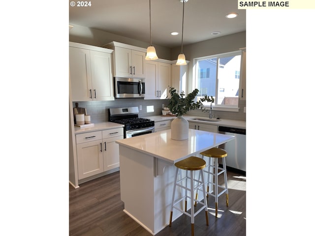 2393 W 7th Ave, Junction City, OR 97448 - kitchen with decorative backsplash, white cabinets, stainless steel appliances, a center island, and a kitchen bar