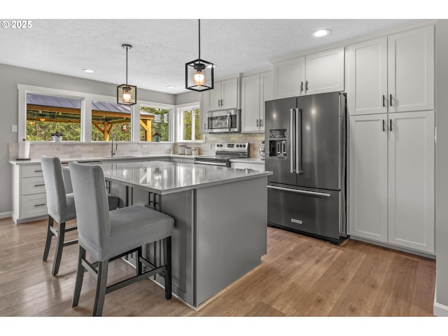 kitchen featuring appliances with stainless steel finishes, tasteful backsplash, and light wood finished floors