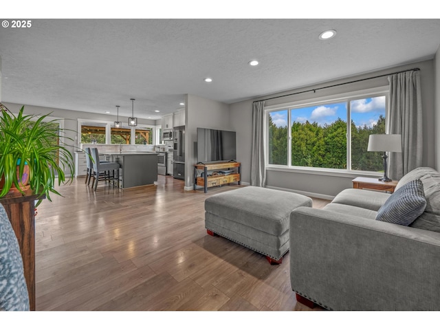 living room with recessed lighting, a textured ceiling, a wealth of natural light, and wood finished floors