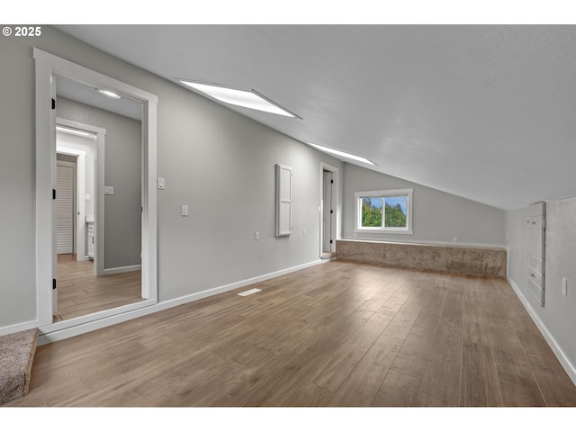 additional living space with baseboards, vaulted ceiling, and wood finished floors