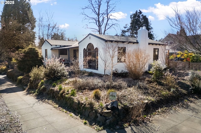 view of front of house featuring stucco siding and a chimney