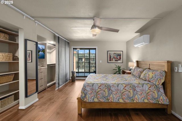 bedroom featuring ceiling fan, a wall mounted AC, and light hardwood / wood-style flooring