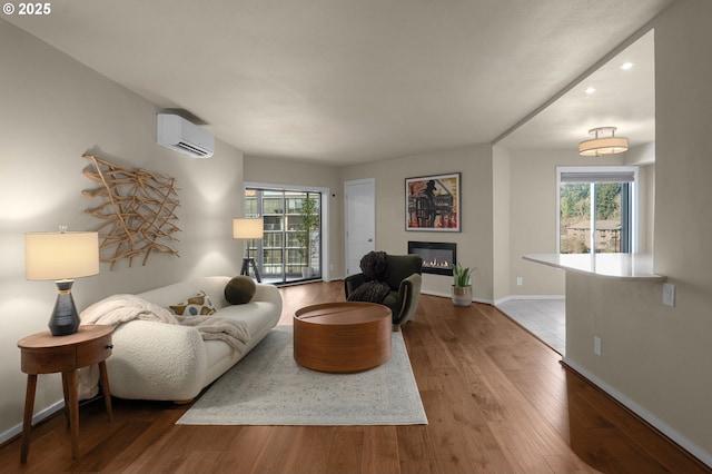 living room featuring hardwood / wood-style flooring, a wealth of natural light, and a wall mounted AC