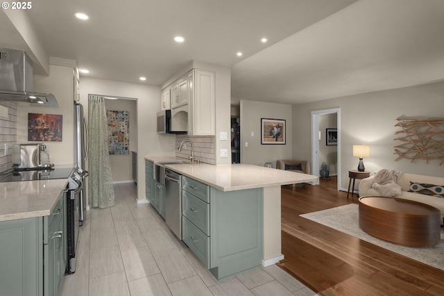 kitchen with appliances with stainless steel finishes, kitchen peninsula, decorative backsplash, sink, and white cabinetry