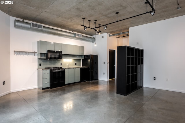 kitchen featuring visible vents, black appliances, gray cabinets, a high ceiling, and concrete flooring