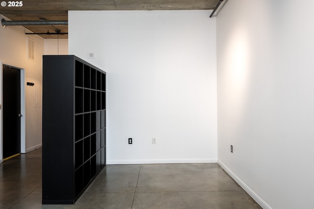 empty room with baseboards, concrete floors, and a towering ceiling