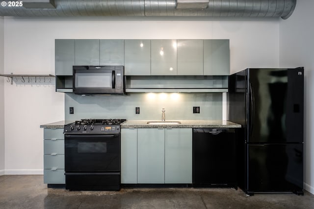 kitchen with tasteful backsplash, concrete floors, light stone countertops, black appliances, and a sink