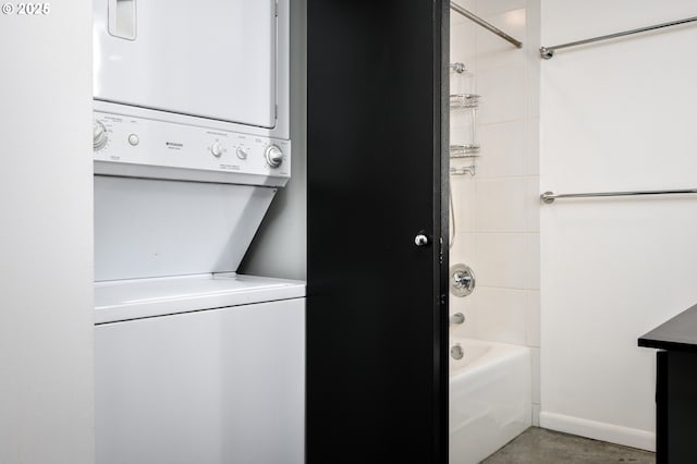 washroom featuring laundry area, baseboards, and stacked washer / drying machine