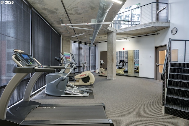 exercise room with a towering ceiling and carpet floors