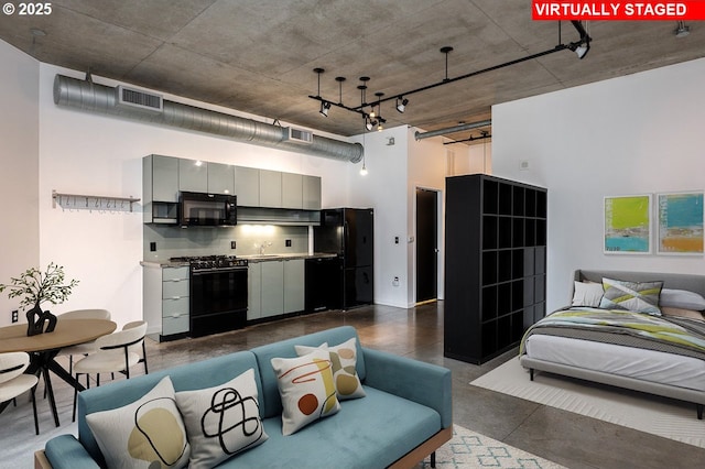 bedroom featuring visible vents, concrete floors, freestanding refrigerator, and a high ceiling