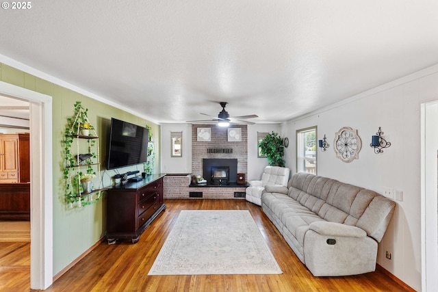 2720 Bowman Rd, Reedsport, OR 97467 - living area featuring ceiling fan, wood finished floors, a brick fireplace, and crown molding