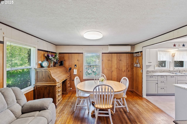 2720 Bowman Rd, Reedsport, OR 97467 - dining space featuring light wood-type flooring, wood walls, and an AC wall unit