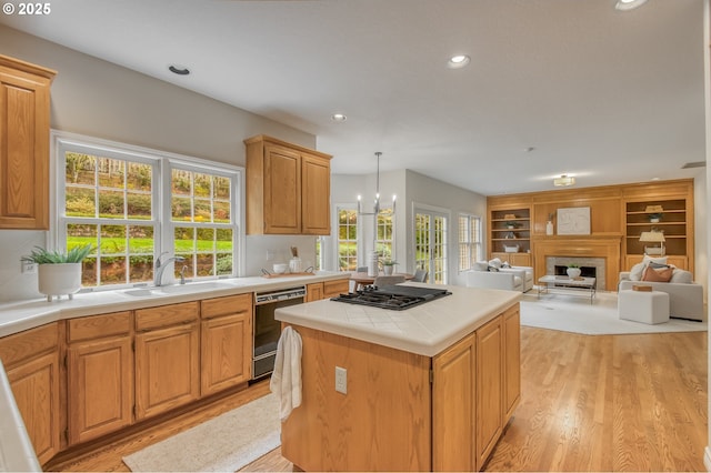 kitchen featuring gas cooktop, a kitchen island, a sink, dishwasher, and light wood-type flooring