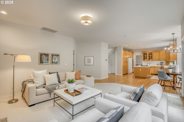 living area with visible vents, baseboards, light wood-type flooring, recessed lighting, and a notable chandelier