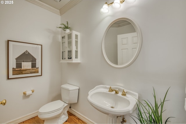 half bathroom featuring baseboards, toilet, ornamental molding, wood finished floors, and a sink