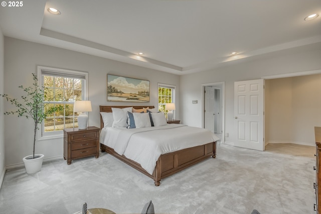 bedroom featuring recessed lighting, light colored carpet, a raised ceiling, and baseboards