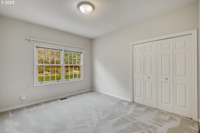 unfurnished bedroom with visible vents, a closet, carpet floors, and baseboards