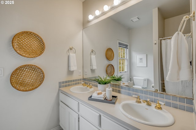 full bath with double vanity, visible vents, toilet, and a sink