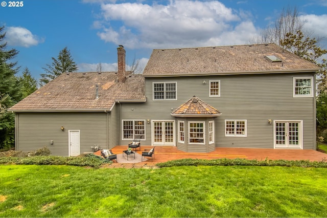 rear view of house featuring french doors, a patio, a yard, and a chimney